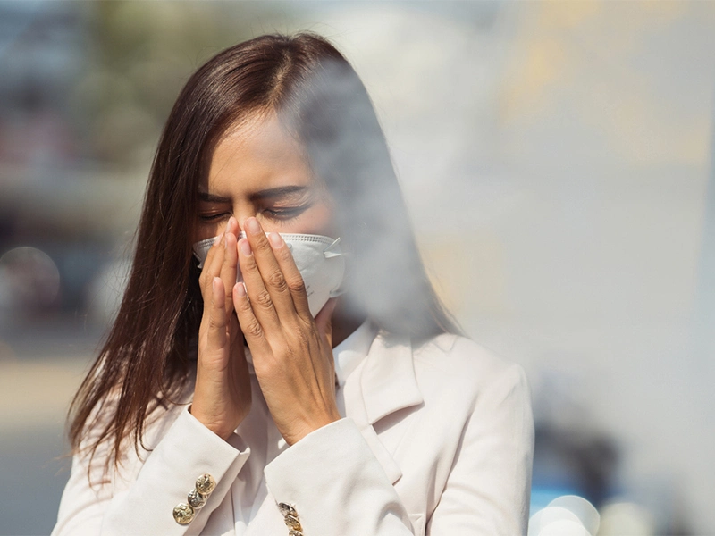 A girl sneezing and protecting herself from city pollution
