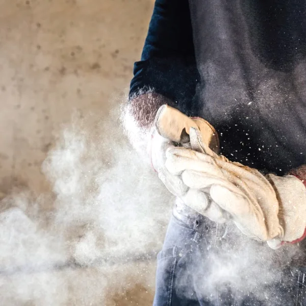 Dust blown from the gloves of a workers